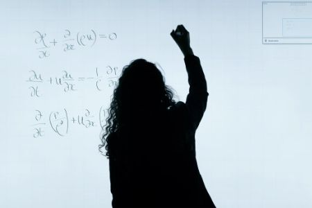 woman writing maths on whiteboard