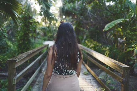 woman starting a journey over a bridge in a rainforrest